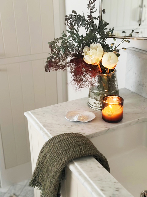 Floral arrangement and candle beside a marble counter