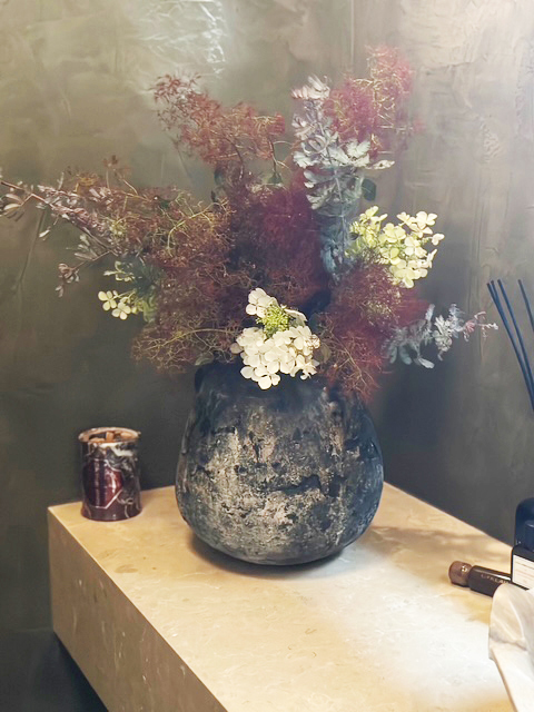 Sculptural floral arrangement against a textured wall