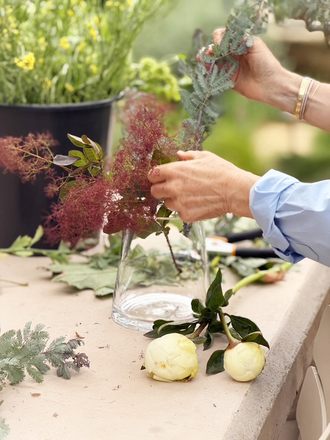 Hands arranging fresh stems in a glass vase
